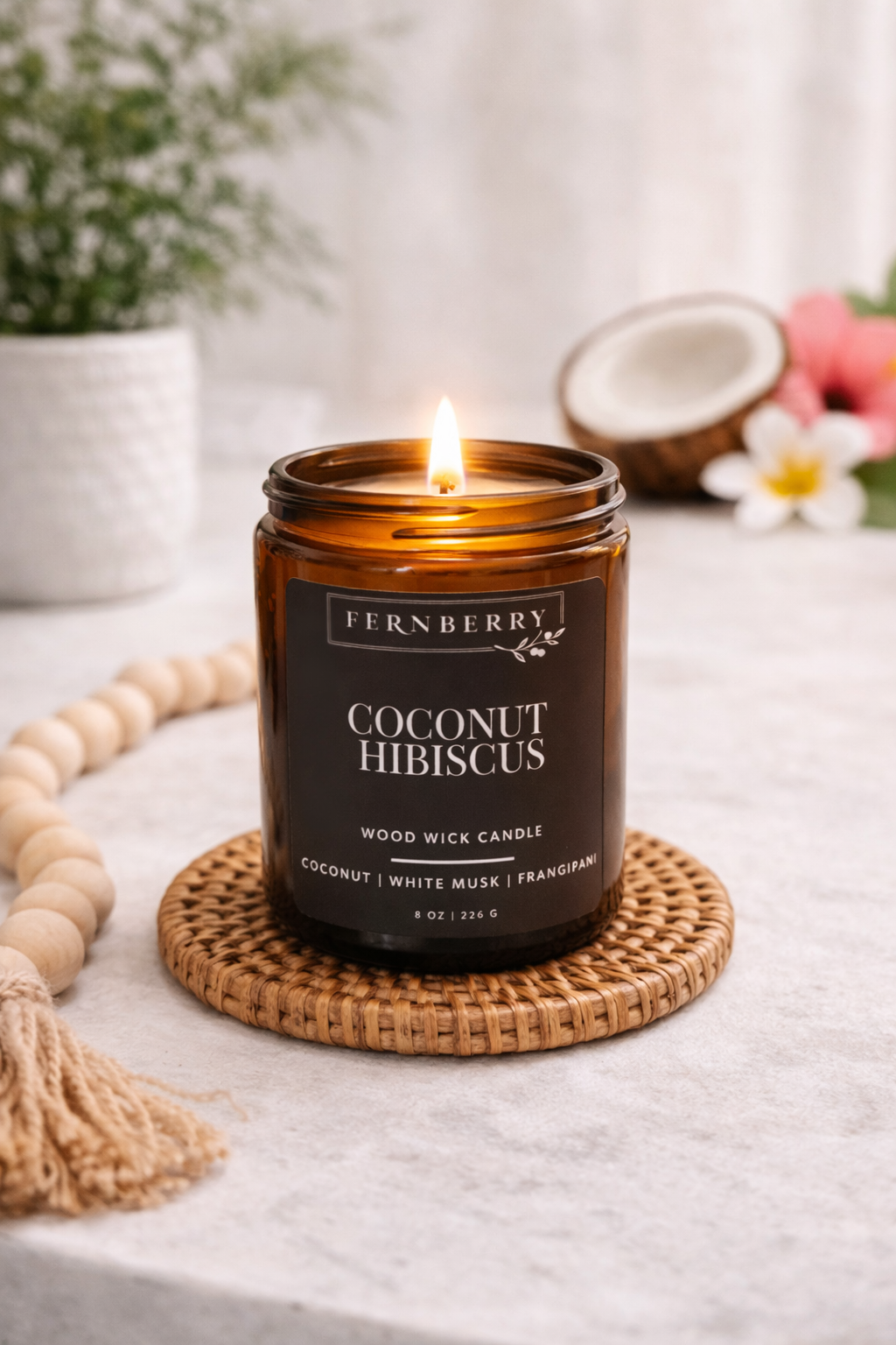 Fernberry coconut hibiscus candle on a woven coaster with a blurred background