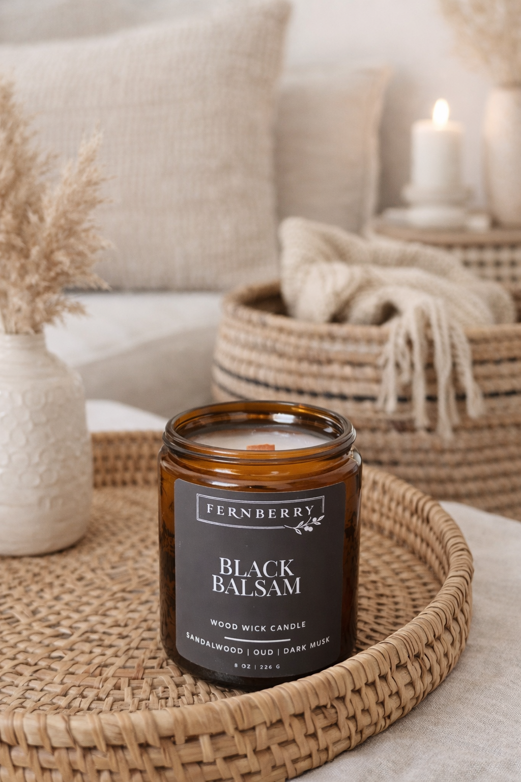 Fernberry Black Balsam candle on a woven tray with a cozy living room background.