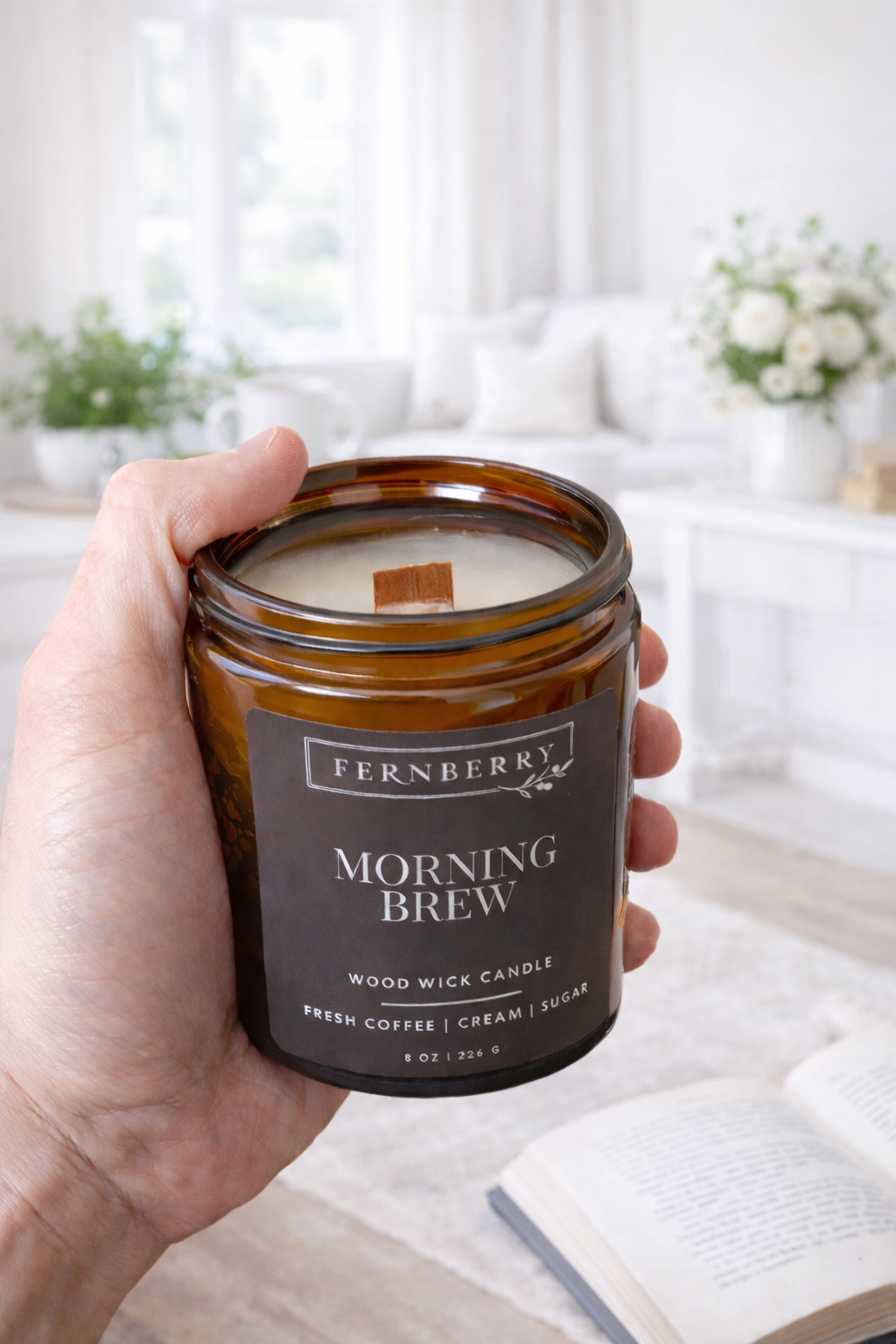 Hand holding a 'Morning Brew' candle with a blurred kitchen background