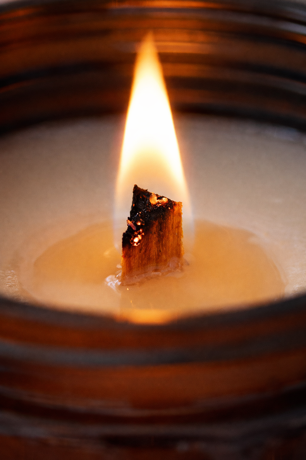 Close-up of a candle with a small wick inside, showing the flame and wax.