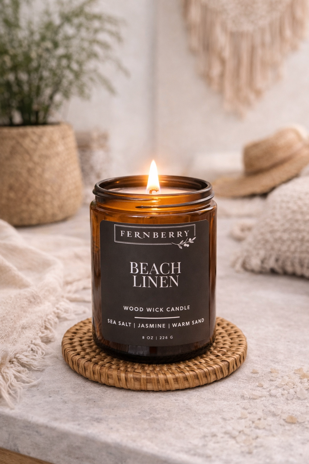 Fernberry Beach Linen candle on a coaster with a blurred background