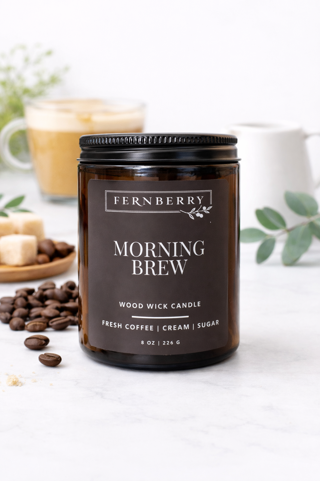 Fernberry Morning Brew candle on a white surface with coffee beans and a blurred coffee cup in the background.