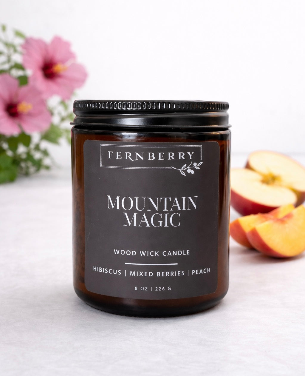 Fernberry Mountain Magic candle with apples and flowers in the background