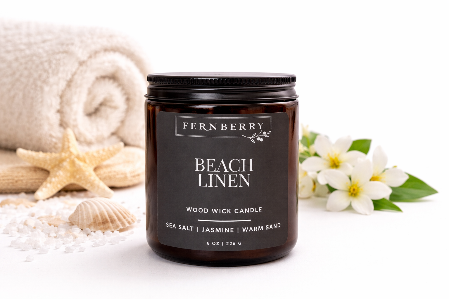 Fernberry Beach Linen candle with beach-themed decor including a towel, starfish, and flowers.