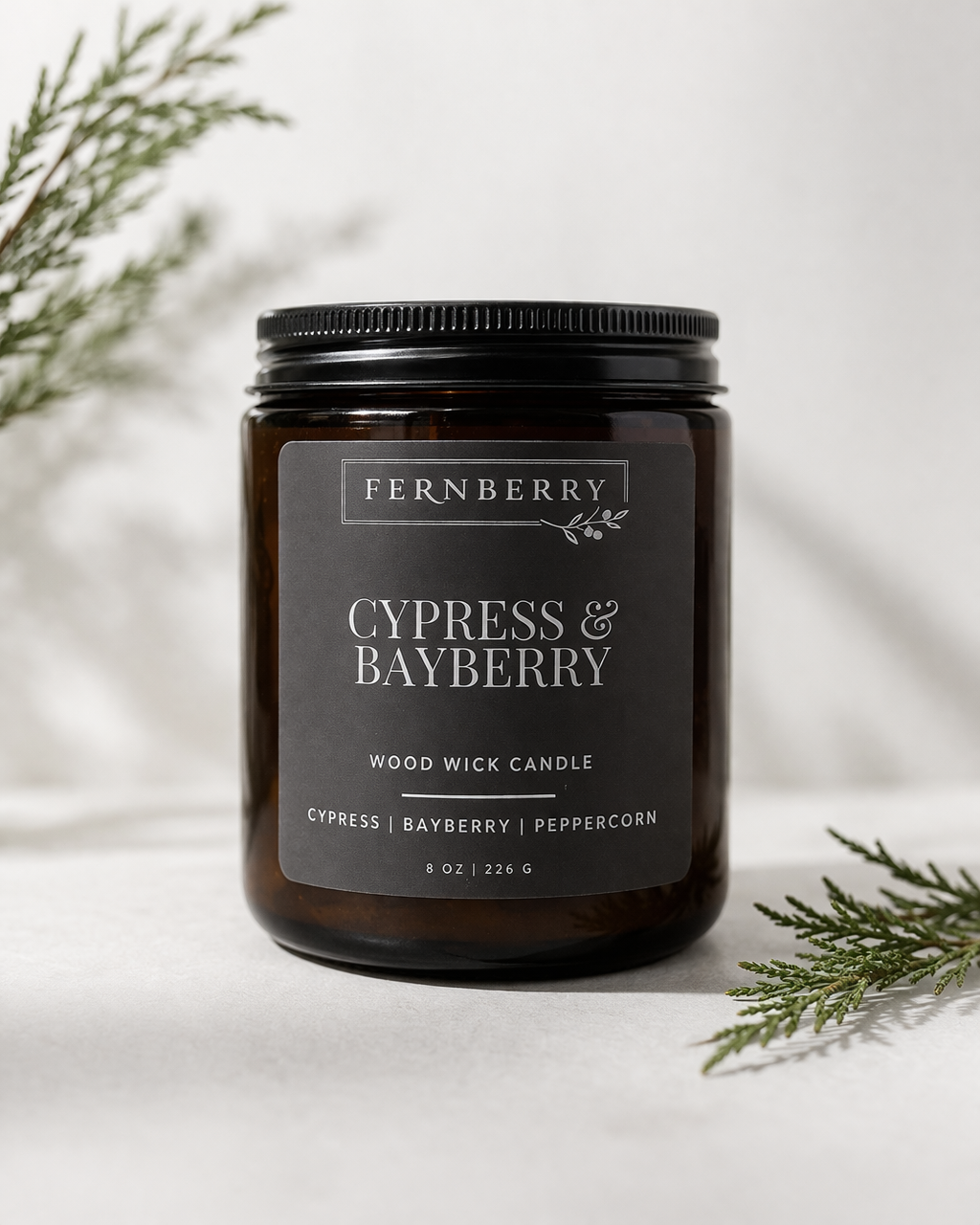Fernberry Cypress & Bayberry candle with greenery on a light background